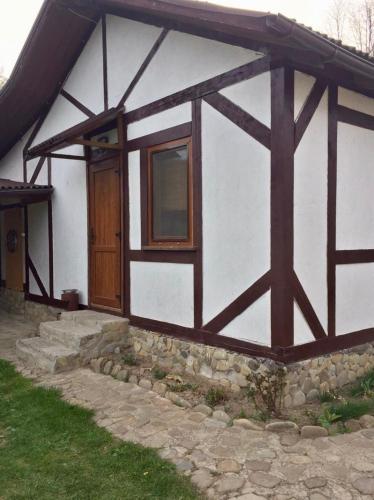 a white and brown building with a wooden door at Tsisarske Urochyshe in Rozgirche