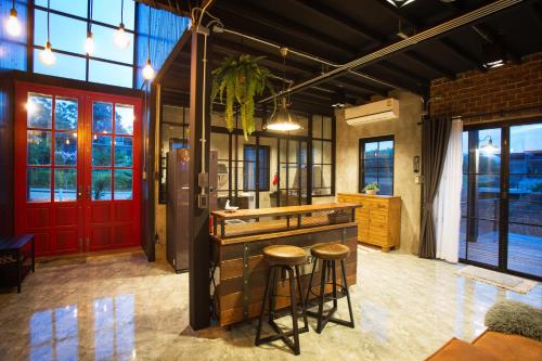 uma cozinha com um bar com bancos e uma porta vermelha em Stella Moonlight Khaoyai em Pong Talong
