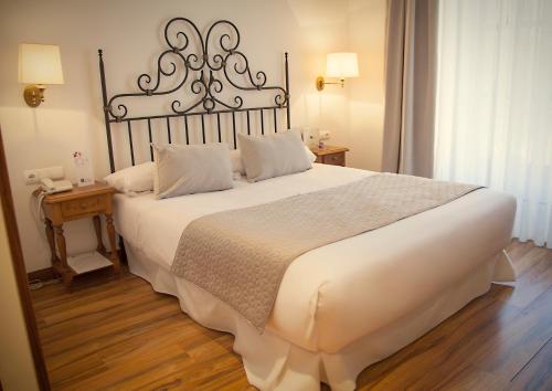 a bedroom with a large white bed with a metal headboard at Palacio Azcárate Hotel in Ezcaray