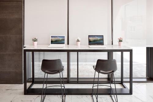 two laptops on a table with two chairs at Ramada Encore by Wyndham Gimpo Han River Hotel in Gimpo