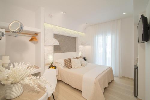 a white bedroom with a bed and a table at Spiros in Naxos Chora