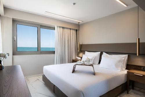 a hotel room with a large bed and a window at Porto Platanias Beach Luxury Selection - Adults Only in Plataniás