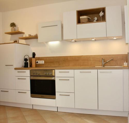 eine Küche mit weißen Schränken und einem Waschbecken in der Unterkunft SchoenHier-Timmendorf in Timmendorfer Strand