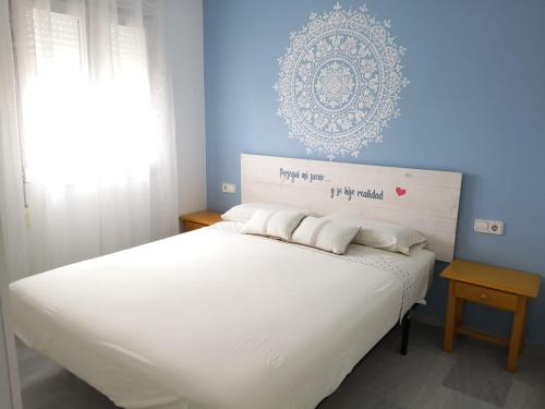 a bedroom with a white bed with a blue wall at Novo Paradise in Chiclana de la Frontera