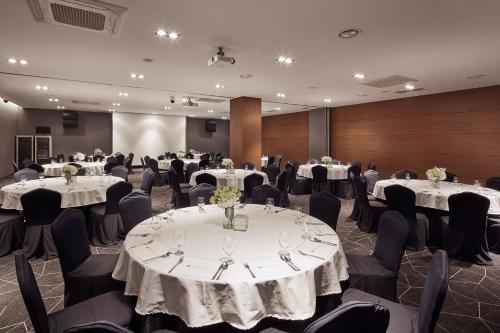 a conference room with tables and chairs with white tablecloths at Ramada Encore by Wyndham Gimpo Han River Hotel in Gimpo