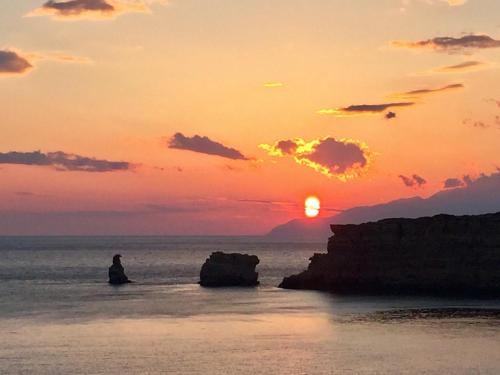 a person sitting in the ocean watching the sunset at Villa Thalassa in Triopetra