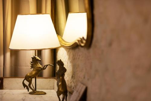 a bronze horse lamp on a table next to a mirror at Hôtel Boutique Saint-Louis in Lisieux