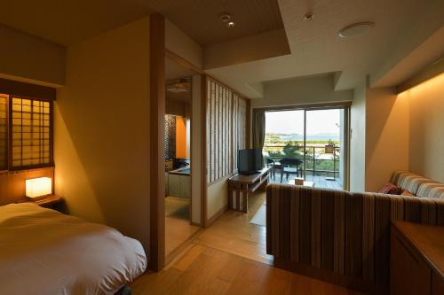 a bedroom with a bed and a balcony with a television at Matsushima Ichinobo in Matsushima
