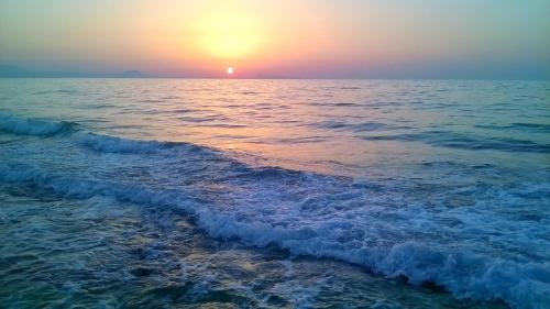 a sunset over the ocean with a wave at Christianna House -Villa in Georgioupolis