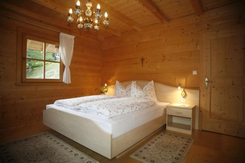 a bedroom with a white bed in a wooden room at Ferienhaus Aussergraben in Ultimo