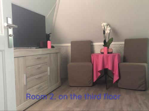 a room with two chairs and a table with flowers on it at B&B nancy in holland met eigen badkamer , independent bathroom in Aalten