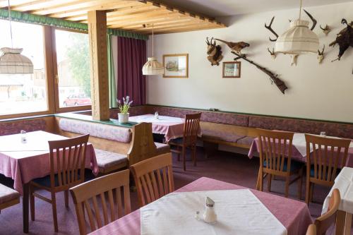 ein Restaurant mit Tischen, Stühlen und einer Bank in der Unterkunft Pension Schweizerhof in Waidring