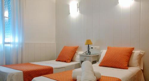 a room with two beds with orange pillows at Elcano in Málaga