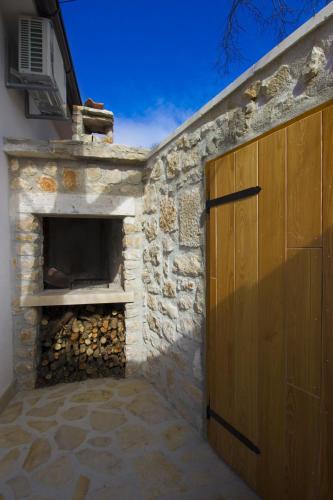 a stone fireplace with a wooden door next to a building at Villa Krcina in Vinišće