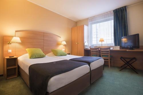 a hotel room with two beds and a television at Campanile Poznan in Poznań