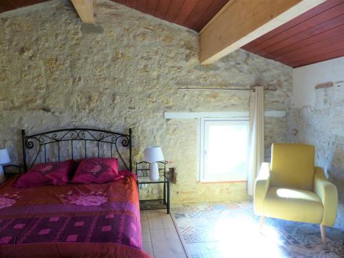 una camera con un letto e una sedia e una finestra di Au Clair De Loup a Saint-Loup