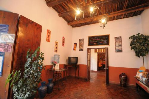 a hallway with a room with a television and plants at Hostal Recoleta Sur in Sucre