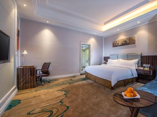 a hotel room with a bed and a table with oranges on it at Vienna International Hotel Guangdong Puning Sqaure in Puning