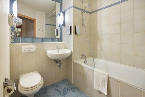 a bathroom with a toilet and a sink and a tub at Campanile Poznan in Poznań