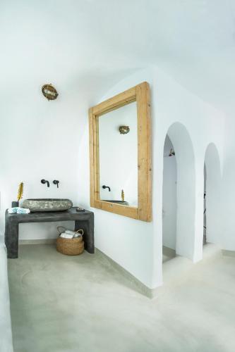 a mirror on a wall with a bench and a table at Sophia Oia View in Oia