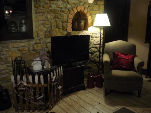 a living room with a tv and a chair and a lamp at Casa Rural La Retuerta in Nava
