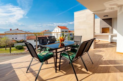 eine Terrasse mit einem Tisch und Stühlen auf dem Balkon in der Unterkunft Apartments Kudec in Malinska