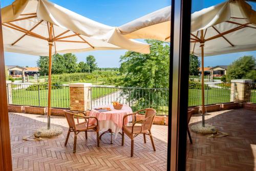 a patio with a table and chairs and umbrellas at Agriturismo Tenuta Regina - Glamping luxury lodges and apartments in Palazzolo dello Stella
