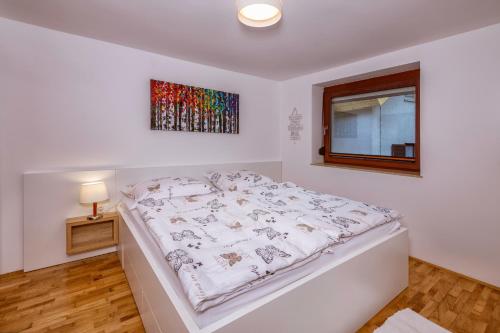 a white bed in a room with a window at Apartments Skodlar in Bled