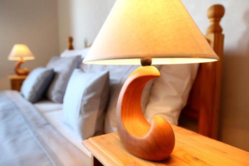 a wooden lamp on a table next to a bed at Hotel Zámeček Janovičky in Broumov
