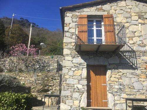 ein Steingebäude mit einer Holztür und einem Balkon in der Unterkunft Vista Portofino in Rapallo