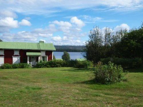 ein rotes Haus mit einem grünen Dach neben einem See in der Unterkunft Holiday Home Raanumaja ii by Interhome in Lampsijärvi
