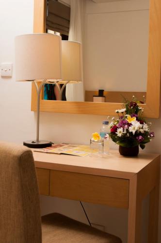 a desk with a lamp and a vase of flowers on it at Bali Relaxing Resort and Spa in Nusa Dua