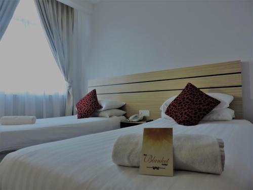 a hotel room with two beds with a book on it at The Blanket Hotel Seberang Jaya in Perai