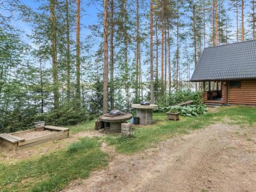 a cabin with a picnic table and benches in the woods at Holiday Home Iltarusko by Interhome in Vuoriniemi