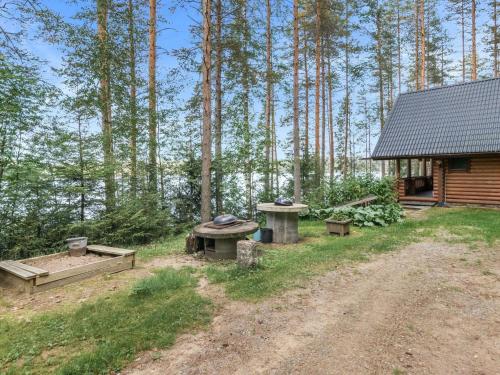 une cabane avec une table de pique-nique et des bancs dans les bois dans l'établissement Holiday Home Iltarusko by Interhome, à Vuoriniemi