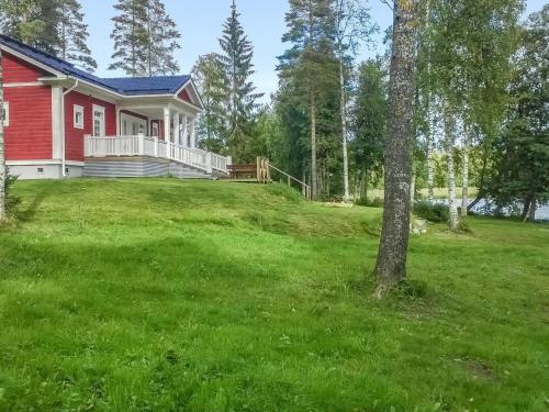 una casa roja en una colina con un patio verde en Holiday Home Villa elisabet by Interhome, en Löytö