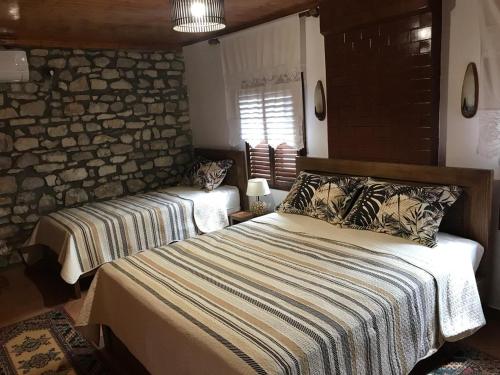 a bedroom with two beds and a stone wall at Guesthouse Arjan in Berat