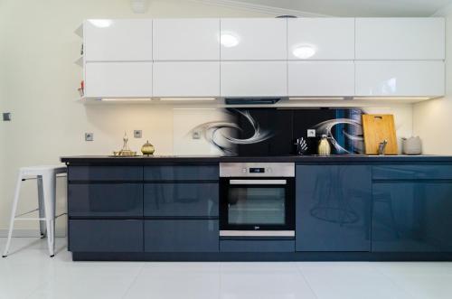 a blue kitchen with white cabinets and an oven at Apartment Evita in Sopot