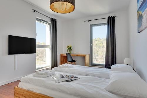 a bedroom with a large white bed with a flat screen tv at GRANO FLATS Gdańsk - Apartament Nadmorze in Gdańsk