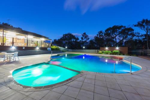 a swimming pool at night with a building in the background at Alivio Tourist Park Canberra in Canberra
