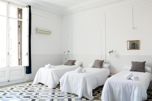 three beds in a white room with a checkered floor at My Address in Barcelona in Barcelona