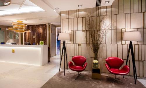 a lobby with two red chairs and a wall at Preciados in Madrid