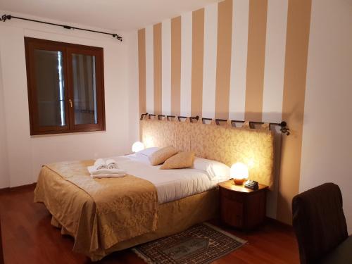 1 dormitorio con 1 cama con pared a rayas en Locanda Da Vittorio, en Manerba del Garda
