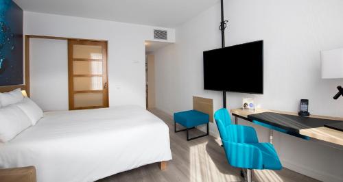 a hotel room with a bed and a desk with a television at Novotel Barcelona Cornellà in Cornellà de Llobregat