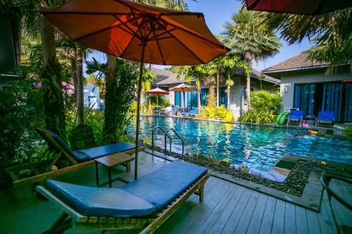 a swimming pool with two chairs and an umbrella at Seava House Ao-Nang Krabi in Ao Nang Beach