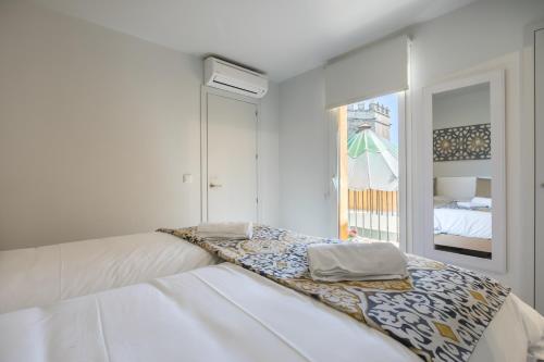 a white bedroom with a bed and a window at Casa Temprado in Seville