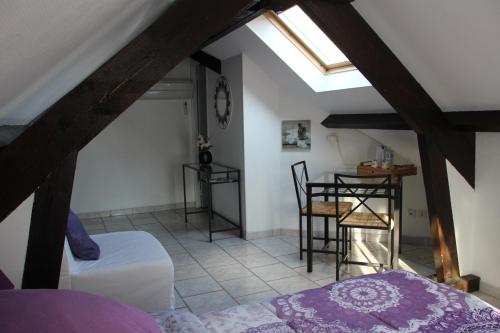a attic room with a bed and a table at La Rose des Vents in Saint-Germain-sur-Morin