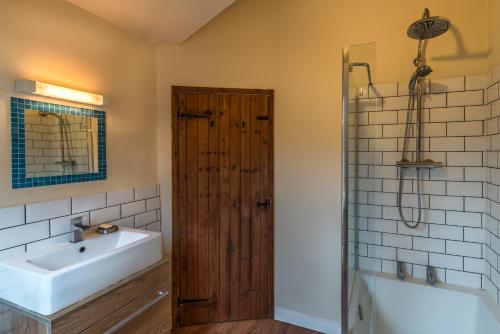 y baño con lavabo, bañera y ducha. en Bramley Cottage, en Ottery St Mary