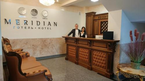 um homem e uma mulher de pé num balcão num salão em Hotel Meridian em Brody