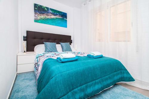een slaapkamer met een bed met twee blauwe kussens bij Espanatour RAFAL in Torrevieja